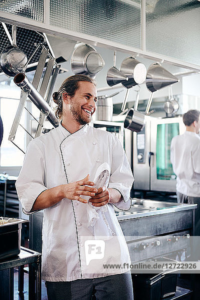 Smiling male chef holding napkin in commercial kitchen