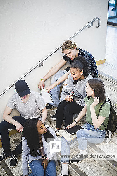 High angle view of multi-ethnic students talking and sitting on steps at high school