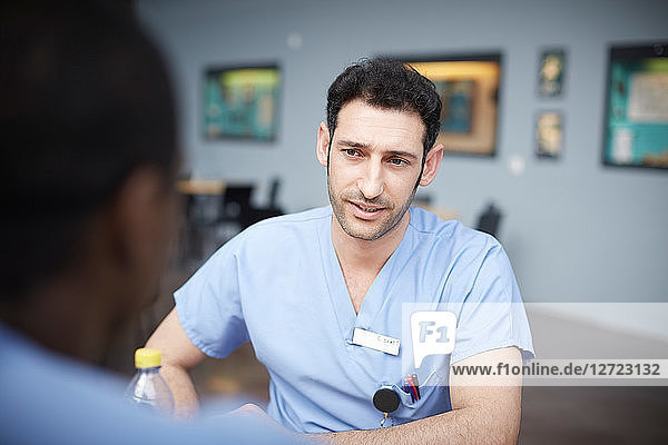 Confident male nurse talking with coworker at hospital cafeteria