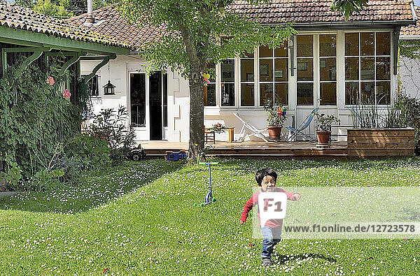 Dreijähriger kleiner Junge läuft im Garten
