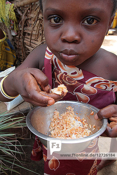 Kleines togolesisches Mädchen  das mit den Händen eine Schüssel Reis isst. Lome. Togo.