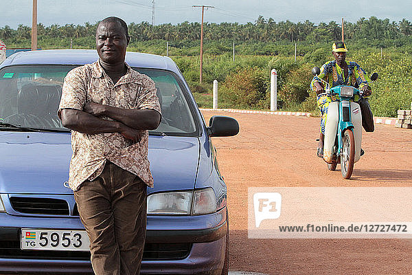 Taxi Benin sitting on the hood of his vehicle. Ouidah. Benin.