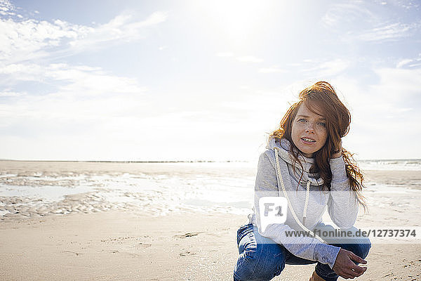 Redheaded woman relaxing on the beach  crouching