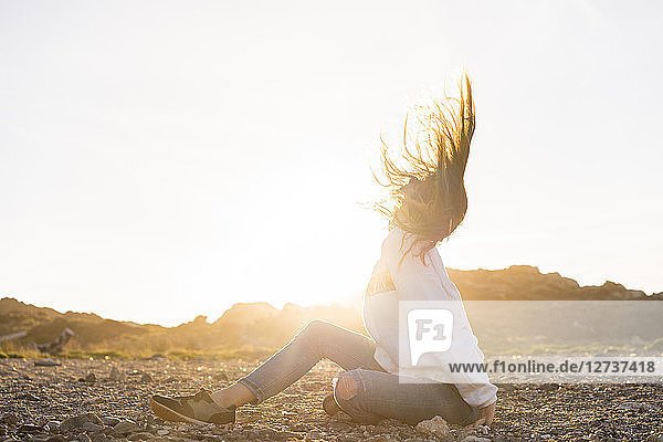 Young woman at the beach  tossing hair at sunset