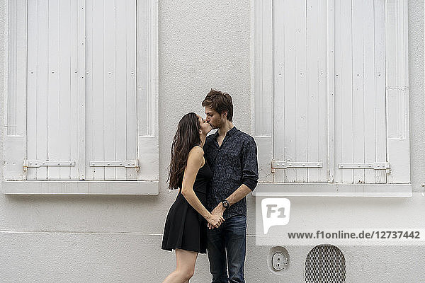 Young couple in love kissing in front of building