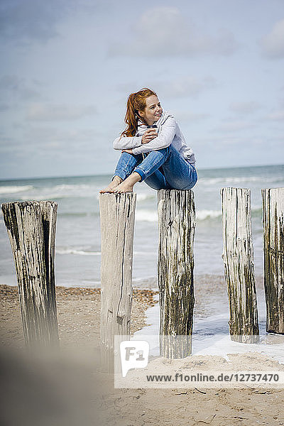 Woman sitting on fence at the sea  drinking tea