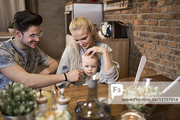 Happy young parents spending time in kitchen at home with their baby girl