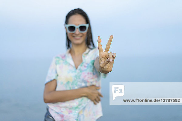 Smiling woman showing victory sign  close-up