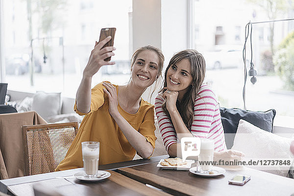Two girlfriends meeting in a coffee shop  taking selfie