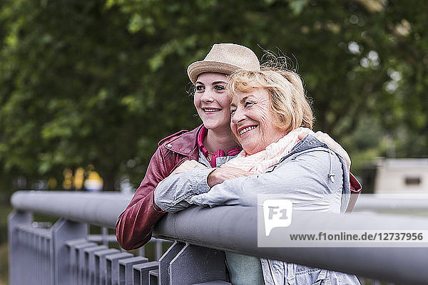 Happy grandmother and granddaughter leaning together on railing