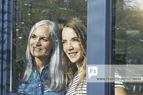 Mother and daughter looking out of window
