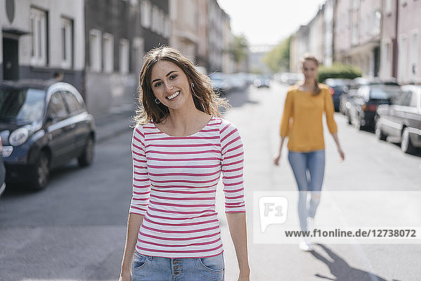 Woman walking in street  followed by friend