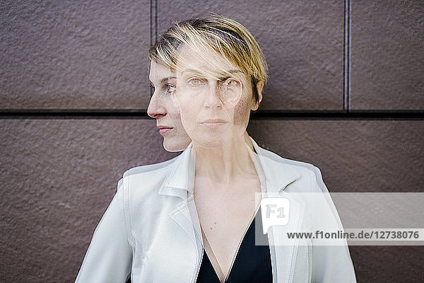 Blond businesswoman leaning against wall  dopple exposure