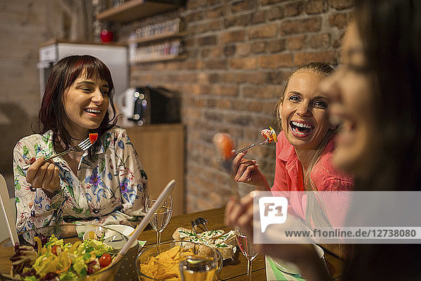 Happy female friends having dinner at home together
