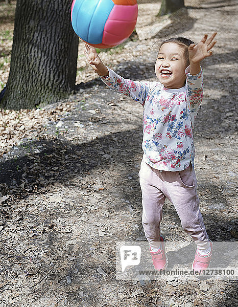 Little girl playng with a ball in a park