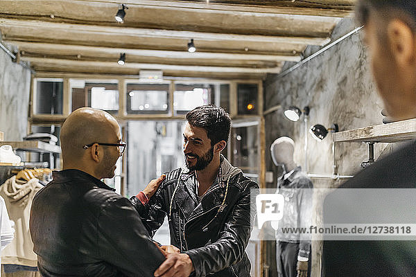 Two smiling men meeting in modern menswear shop