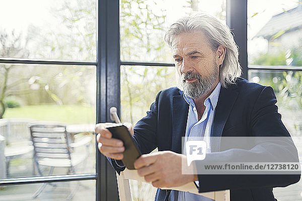 Senior businessman sitting on chair  using smartphone