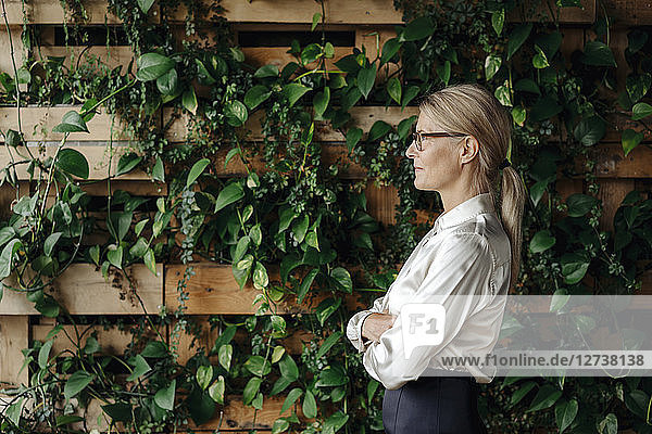Businesswoman at wall with climbing plants