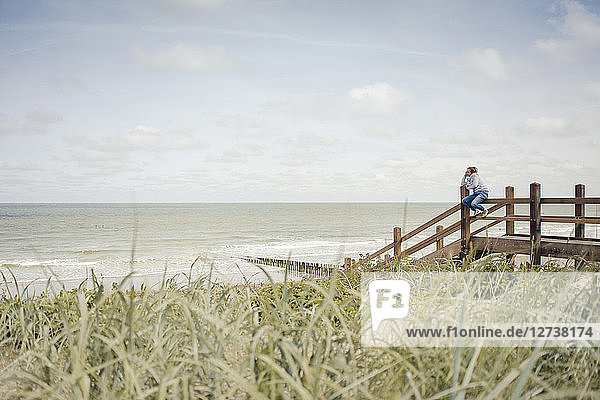 Woman sitting on fence at the beach  relaxing at the sea