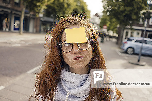 Redheaded woman with adhesive note sticking on her forehead