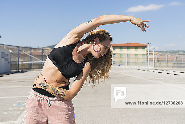 Tattooed young woman doing stretching exercises