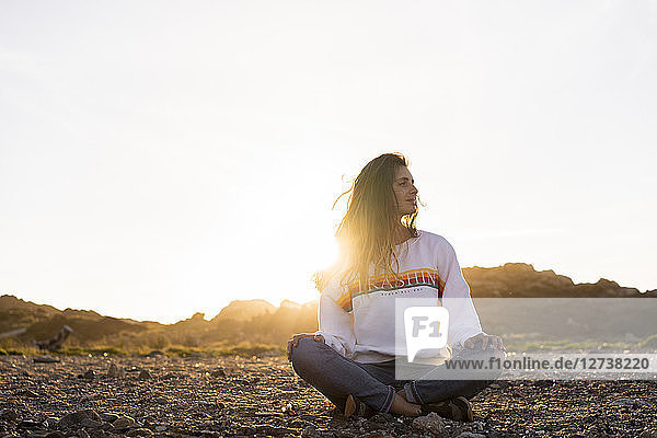 Young woman sitting on the beach  at sunset