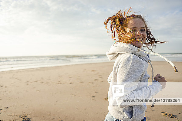 Redheaded woman running on the beach  laughing