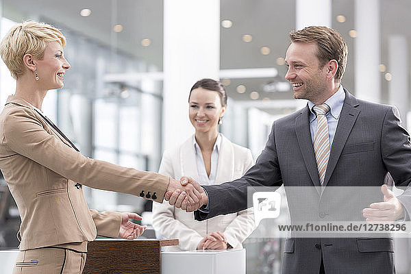 At the car dealer  Happy man and woman shaking hands
