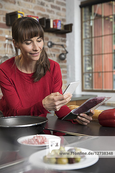 Woman in kitchen scanning products with her smartphone