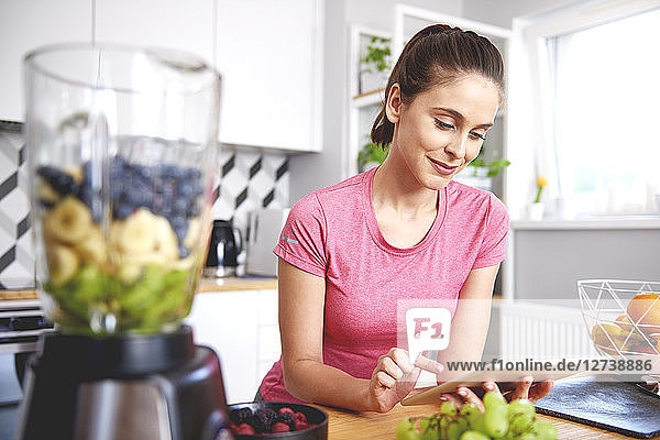 Portrait of smiling young woman using tablet in the kitchen
