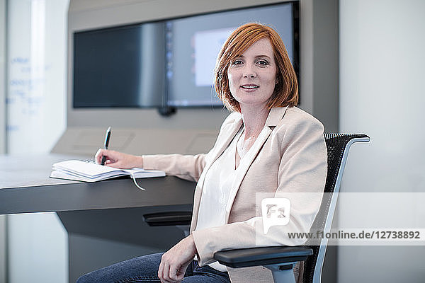 Woman sitting in office with her notebook