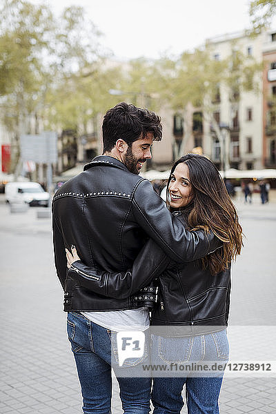 Spain  Barcelona  young couple embracing and walking in the city