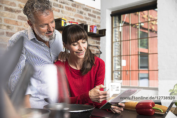 Woman in kitchen scanning products with her smartphone  man looking over her shoulder