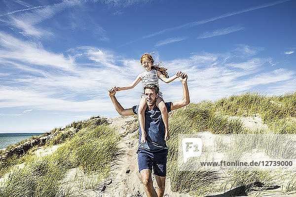 Netherlands  Zandvoort  father carrying daughter on shoulders in beach dunes