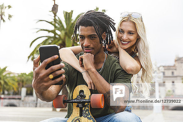 Portrait of multicultural young couple taking selfie with smartphone