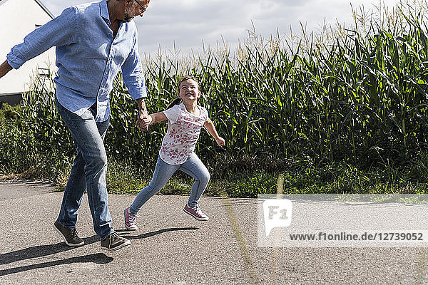 Mature man and little girl running on street  laughing