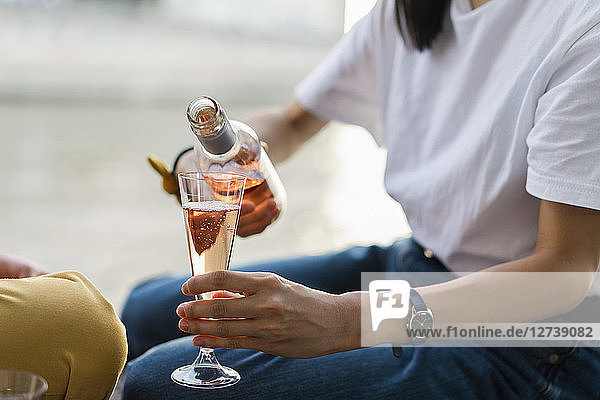 Close-up of woman pouring in sparkling blush wine