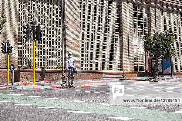 Mature man waiting at crossing with his bicycle