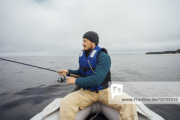 Man sitting on boat fishing with fishing rod