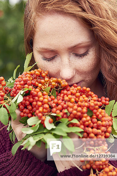 Portrait of freckled redheaded young woman with rowanberries