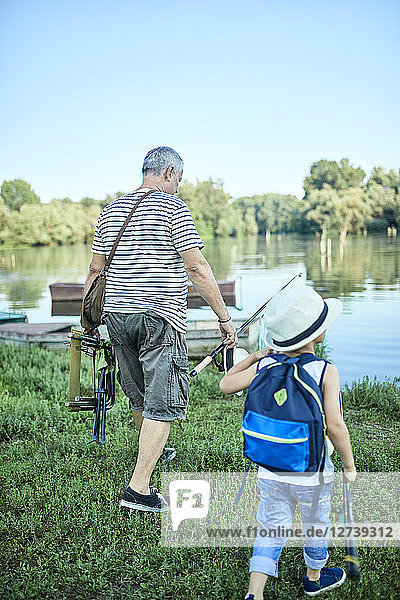Back view of grandfather and grandson with fishing chair and fishing rods