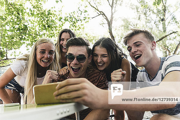 Group of happy friends looking at cell phone outdoors