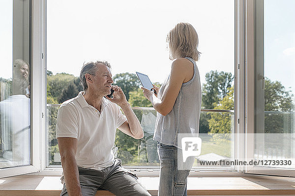 Mature couple with cell phone and tablet at the window