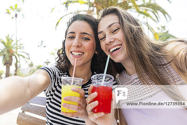 Portrait of two happy female friends enjoying a fresh slush