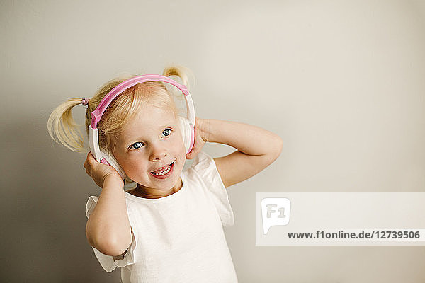 Portrait of little girl listening music with headphones dancing