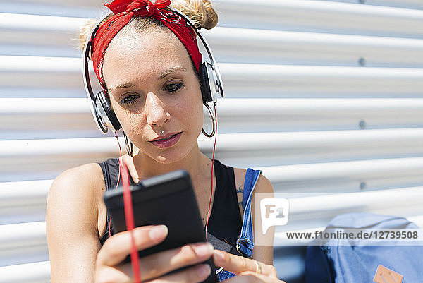 Portrait of young woman with headphones looking at smartphone