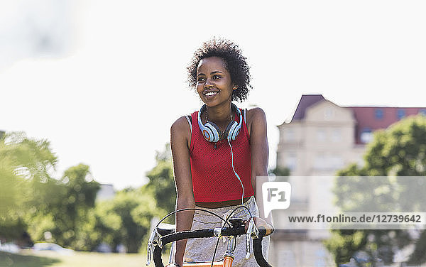 Smiling sporty young woman on bicycle in park
