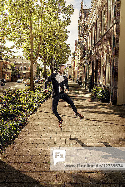 Netherlands  Venlo  happy businessman jumping on pavement