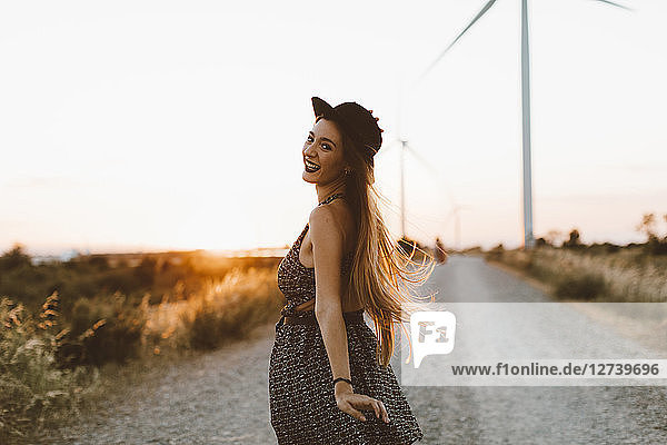 Portrait of smiling young woman on country road at sunset