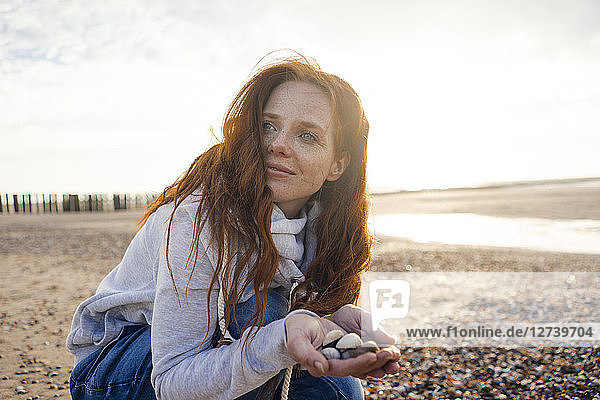 Redheaded woman collecting shell on the beach
